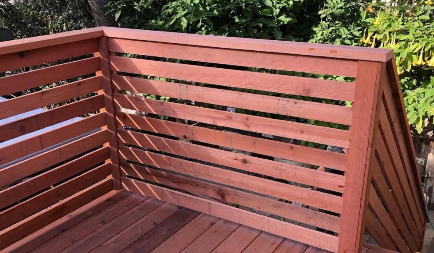 New wooden deck with horizontal slat railing and a hammer on the deck floor